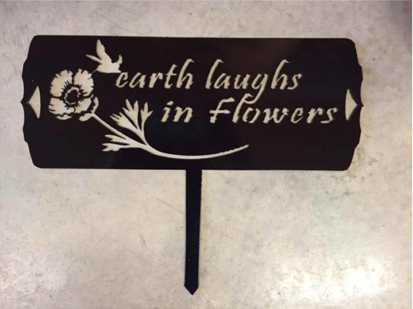 Metal garden sign, earth laughs in flowers